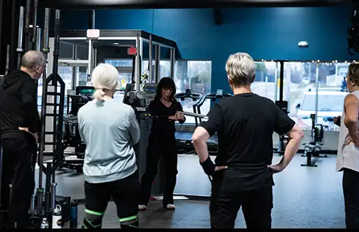 Personal trainer instructing a small group strength training class at State of Fitness gym with functional fitness equipment.
