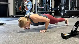 Woman performing a push-up during an online personal training workout with State of Fitness.